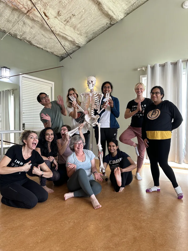 Group of teacher trainees with Michelle Spore and a skeleton anatomy model